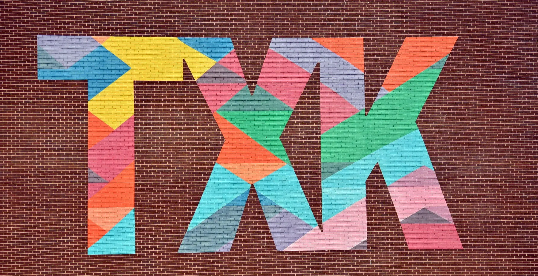 Colorful geometric mural painted across a brick wall