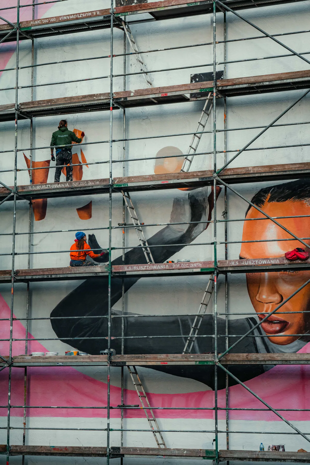 Artists painting a large mural from scaffolding