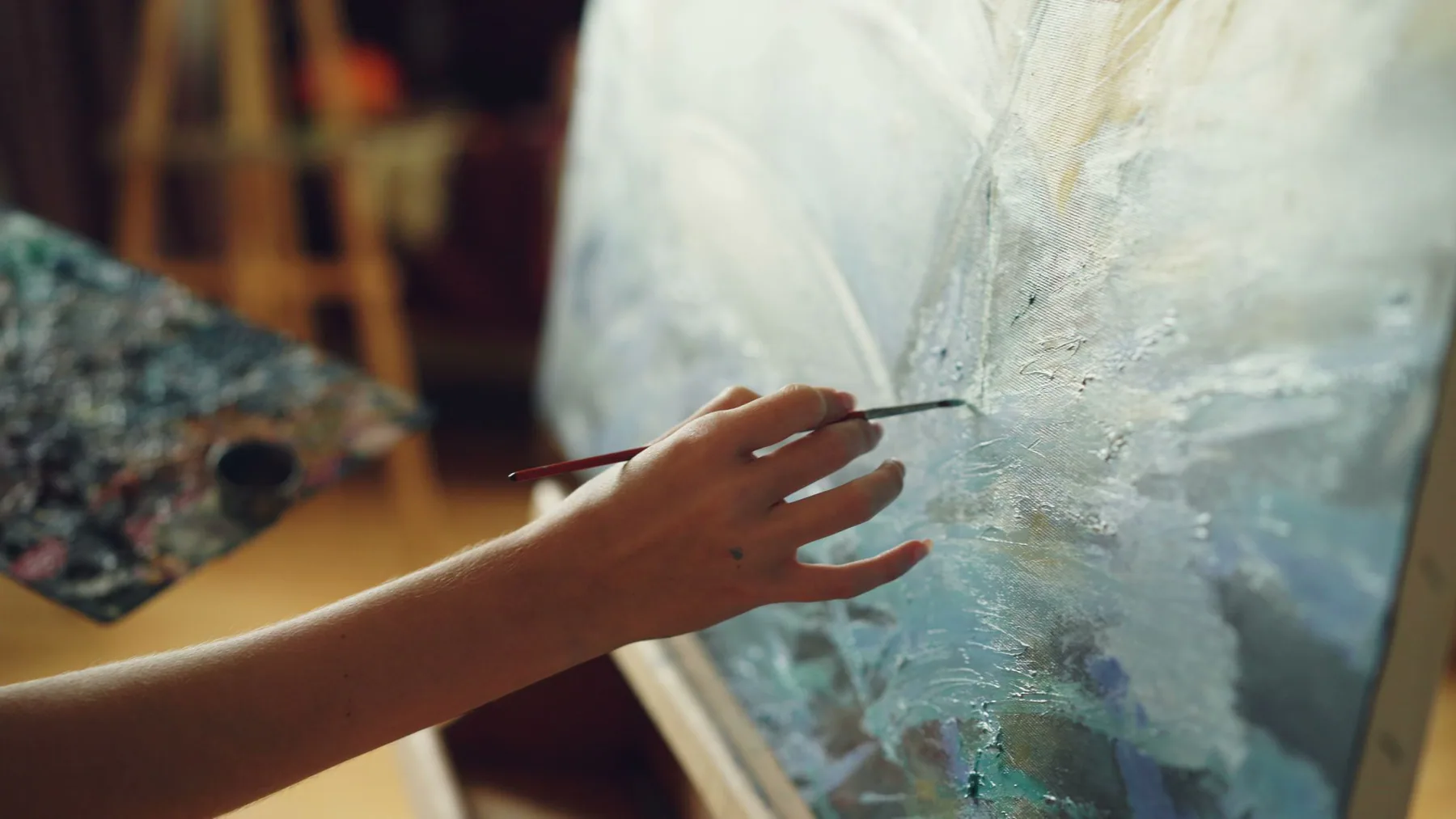 Artist applying fine paint to a textured canvas
