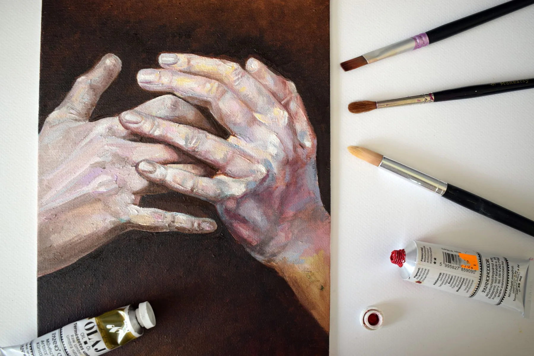 Painted hands study beside brushes and pigment